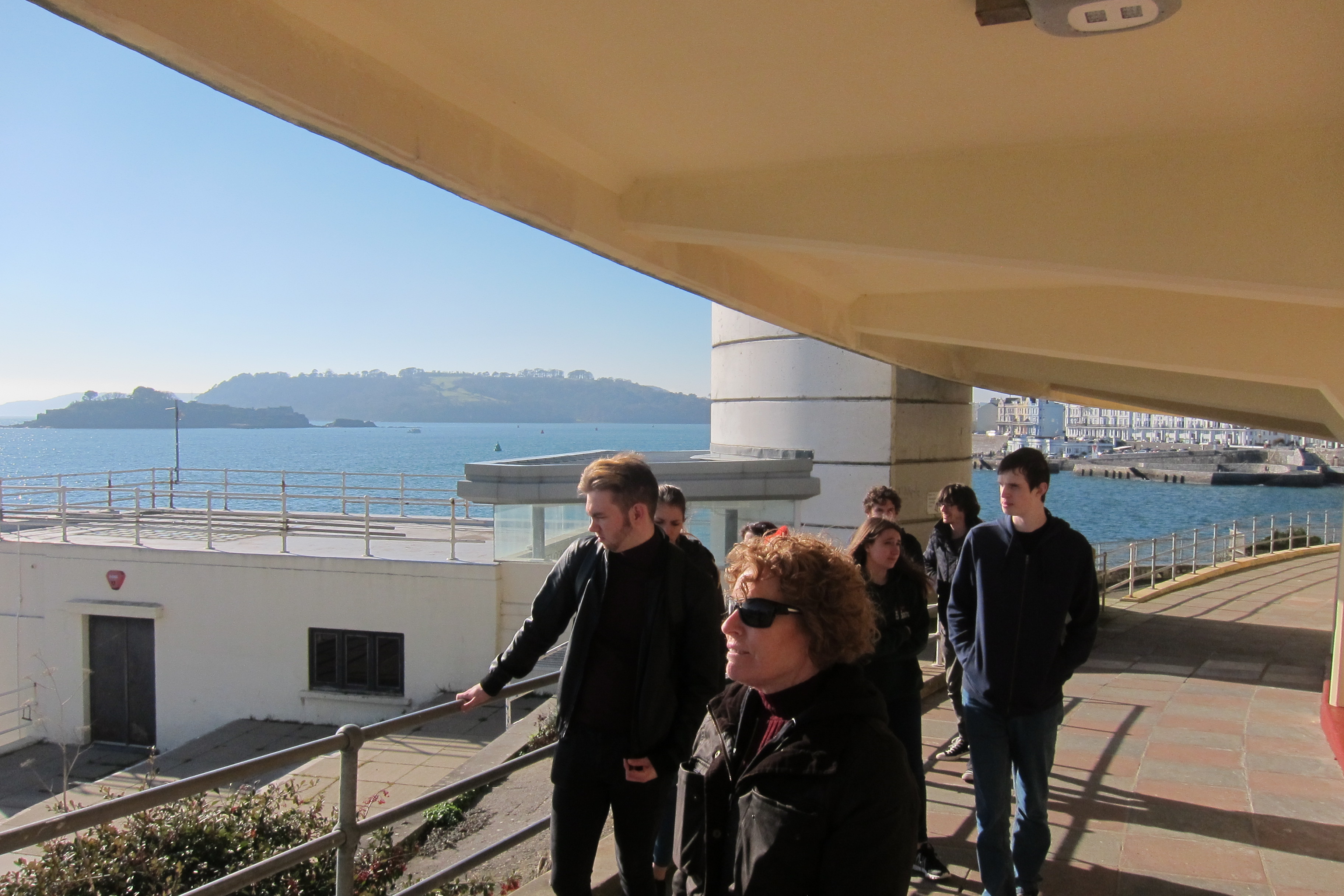 Group of students looking out to sea walking along promenade